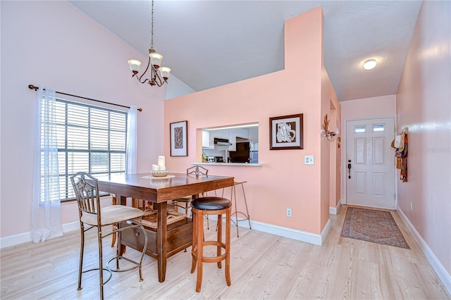 2139 Elm St Unit 308, Dunedin, FL 34698 - dining space featuring a chandelier, light wood-style floors, baseboards, and high vaulted ceiling