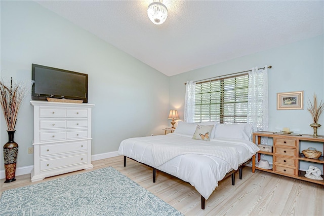 2139 Elm St Unit 308, Dunedin, FL 34698 - bedroom with vaulted ceiling, wood finished floors, baseboards, and a textured ceiling