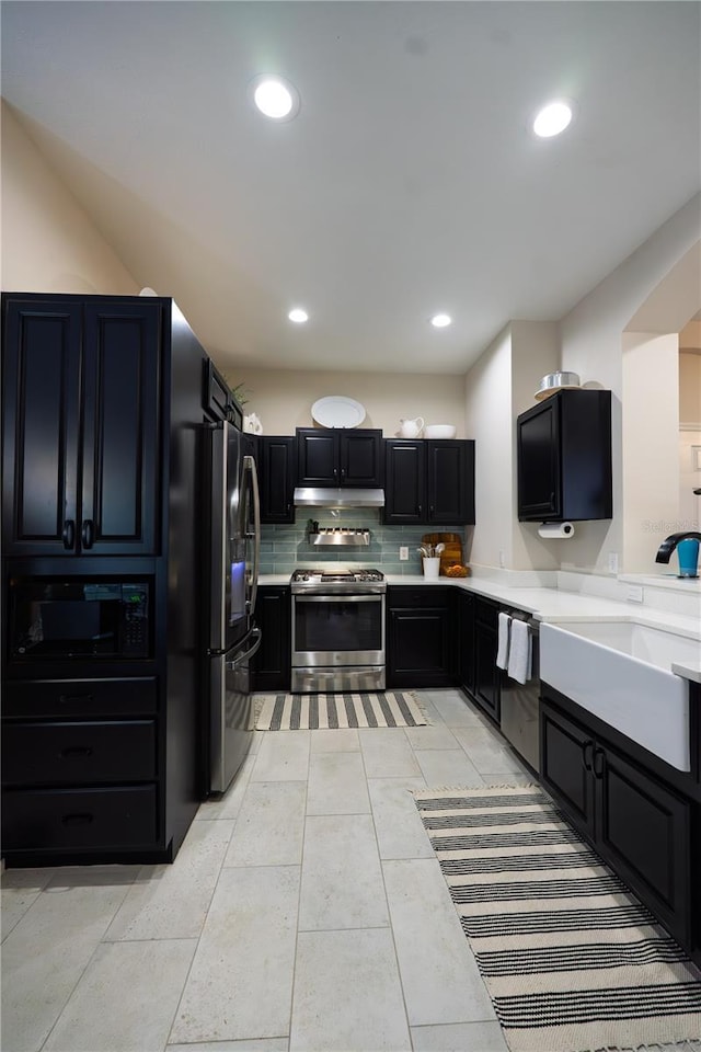 kitchen with appliances with stainless steel finishes, a sink, light countertops, decorative backsplash, and recessed lighting