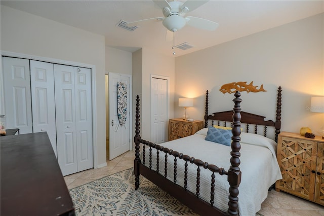 bedroom featuring light tile patterned floors, multiple closets, and a ceiling fan