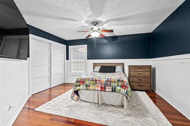 16804 Windsor Park Dr, Lutz, FL 33549 - bedroom featuring a textured ceiling, wainscoting, wood finished floors, a closet, and ceiling fan