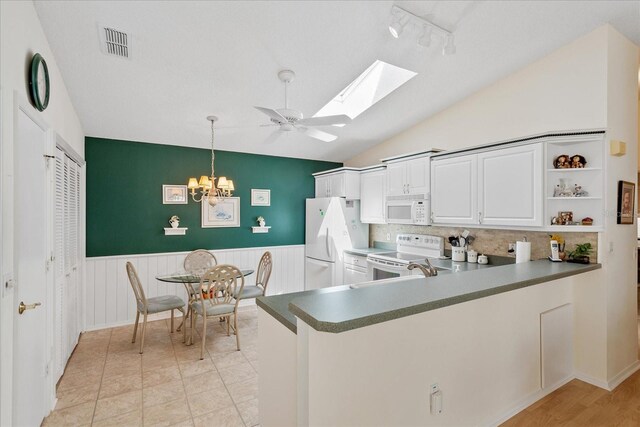 2121 Escobar Ave, Lady Lake, FL 32159 - kitchen featuring white appliances, a skylight, wainscoting, a chandelier, and white cabinetry