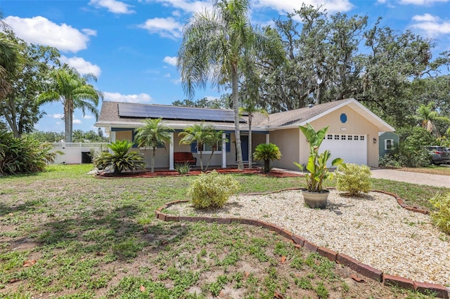 single story home with an attached garage, solar panels, driveway, and covered porch