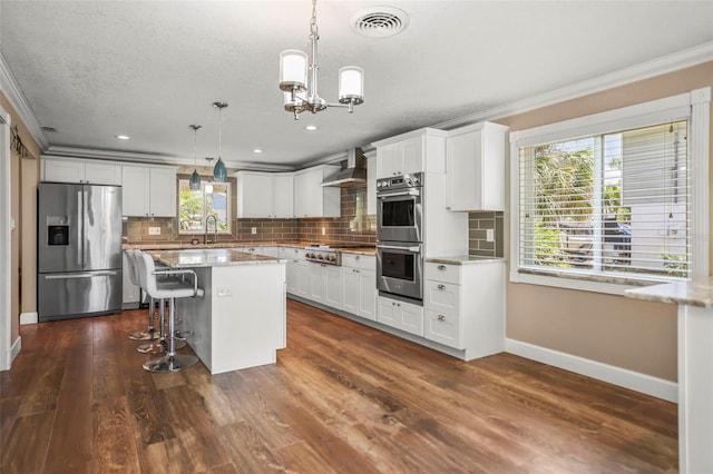 kitchen with stainless steel appliances, crown molding, wall chimney exhaust hood, baseboards, and a sink
