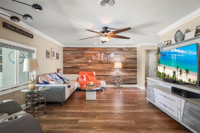 living room with wood walls, ceiling fan, ornamental molding, wood finished floors, and baseboards