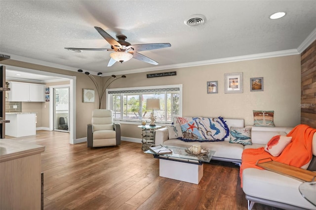 living room with ornamental molding, a ceiling fan, a textured ceiling, baseboards, and wood finished floors