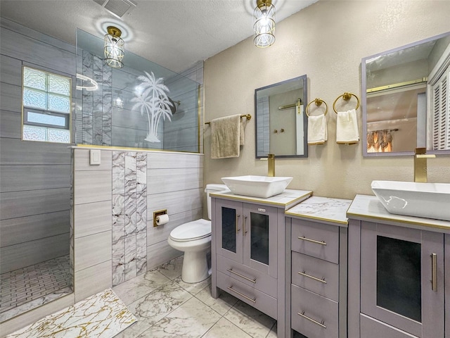 full bath featuring marble look tiles, walk in shower, vanity, toilet, and a textured ceiling