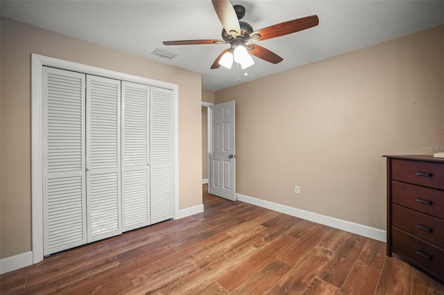 unfurnished bedroom with baseboards, a closet, wood finished floors, and ceiling fan