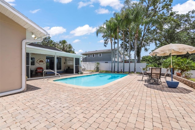 view of pool with a patio area, a fenced backyard, outdoor dining area, and a sunroom