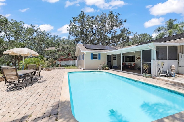 swimming pool with a sunroom, a patio, and outdoor dining area