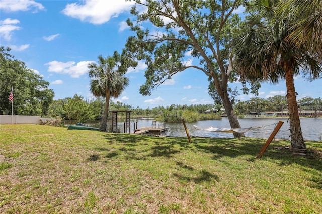 view of green lawn with a water view and a dock