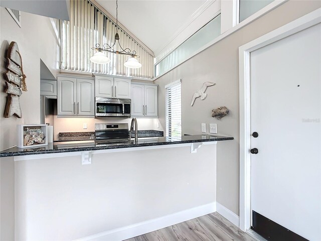 2695 N Seabreeze Pt Unit I1, Crystal River, FL 34429 - kitchen featuring stainless steel appliances, dark stone counters, a kitchen breakfast bar, light wood-style flooring, and lofted ceiling