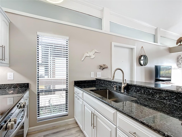 2695 N Seabreeze Pt Unit I1, Crystal River, FL 34429 - kitchen with a sink, dark stone counters, light wood-type flooring, white cabinets, and stainless steel stove