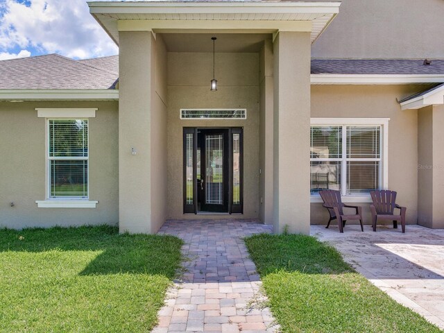 16220 Lake Armistead Way, Odessa, FL 33556 - doorway to property featuring stucco siding, a yard, and a shingled roof