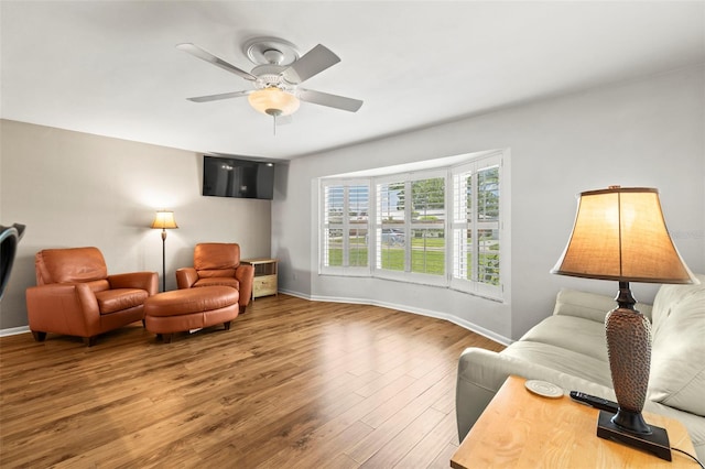 sitting room featuring baseboards, wood finished floors, and a ceiling fan