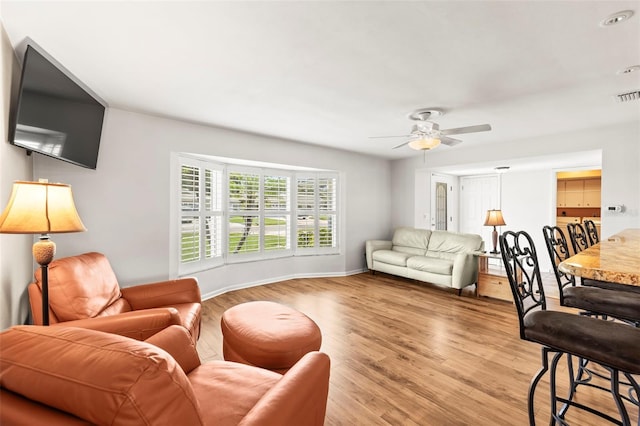 living area with light wood-type flooring, ceiling fan, and baseboards