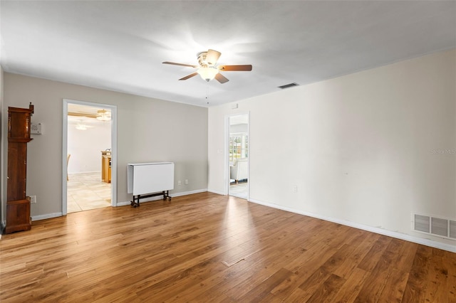 empty room with ceiling fan, light wood finished floors, and baseboards