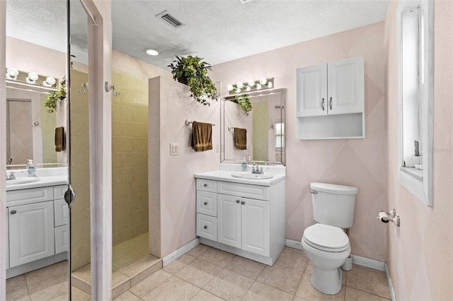 full bathroom with toilet, vanity, tiled shower, a textured ceiling, and baseboards