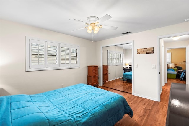 bedroom with light wood-style flooring, a closet, ceiling fan, and baseboards