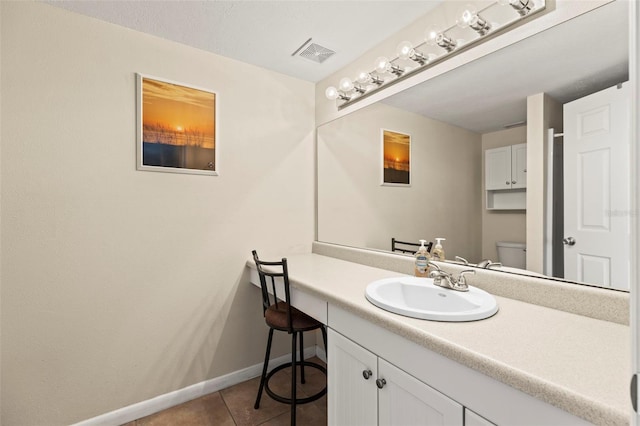 bathroom with toilet, tile patterned floors, vanity, and baseboards