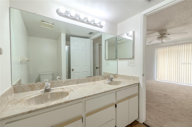 bathroom with toilet, a ceiling fan, and double vanity