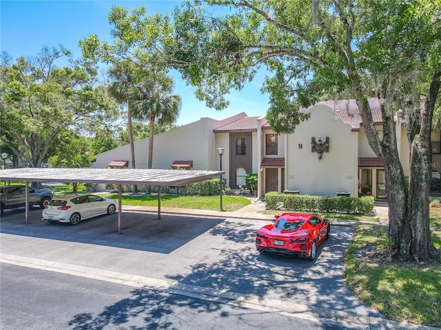 view of front of home with covered parking, a tile roof, and stucco siding