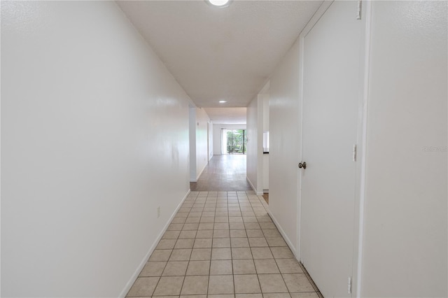 hall featuring light tile patterned floors, baseboards, and recessed lighting