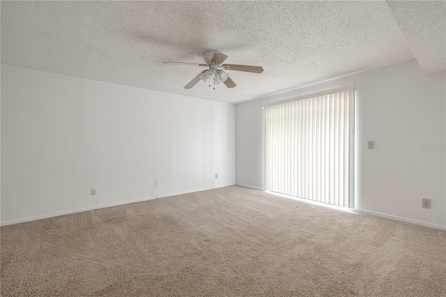 empty room with ceiling fan, a textured ceiling, carpet, and baseboards