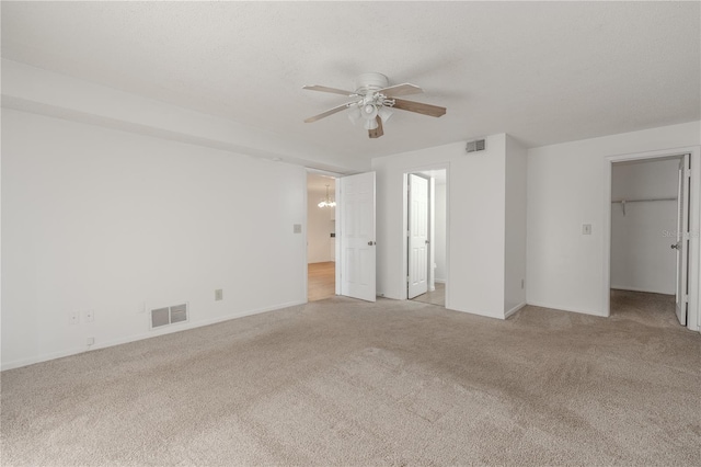 unfurnished bedroom featuring carpet, a walk in closet, baseboards, and a ceiling fan