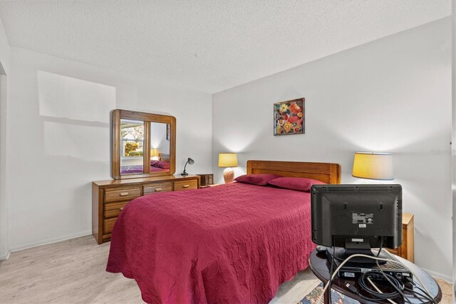 39650 US Highway 19 N Unit 553, Tarpon Springs, FL 34689 - bedroom featuring a textured ceiling, light wood finished floors, and baseboards