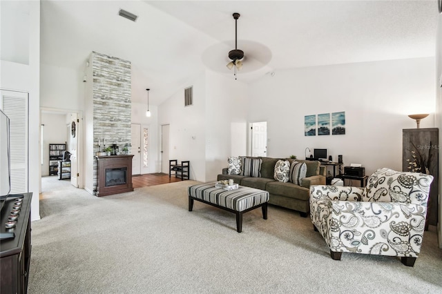 living room featuring carpet floors, a ceiling fan, high vaulted ceiling, and a glass covered fireplace