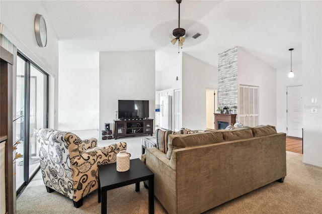 carpeted living room with a fireplace, ceiling fan, plenty of natural light, and high vaulted ceiling