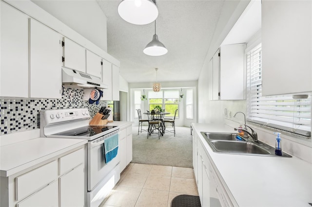 kitchen with white electric stove, under cabinet range hood, light carpet, healthy amount of natural light, and a textured ceiling