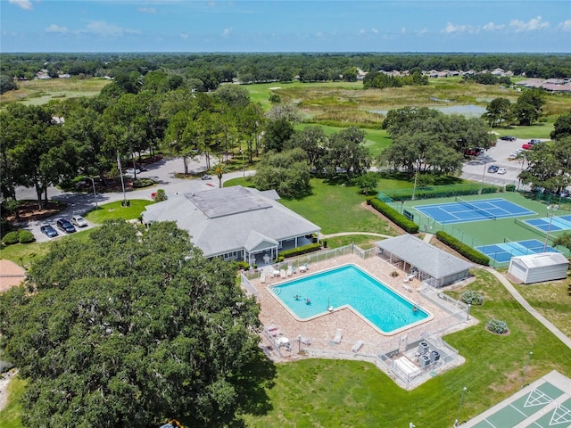 drone / aerial view of a pool area and a tree filled landscape