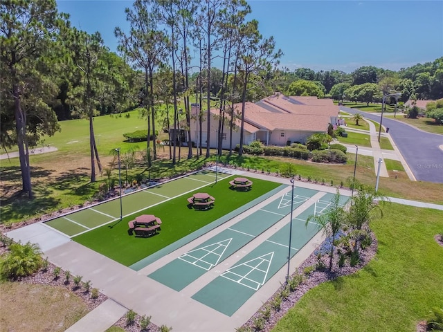 view of home's community featuring shuffleboard, a yard, and view of scattered trees