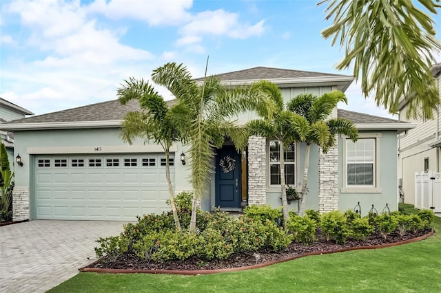 view of front facade with decorative driveway, a garage, stucco siding, and a front lawn