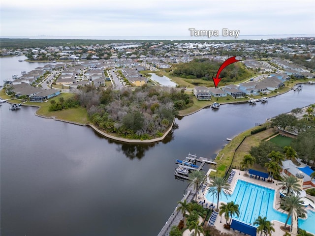 aerial view of property and surrounding area featuring a large body of water, a pool, and nearby suburban area