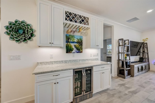 indoor dry bar featuring wine cooler, baseboards, crown molding, and recessed lighting