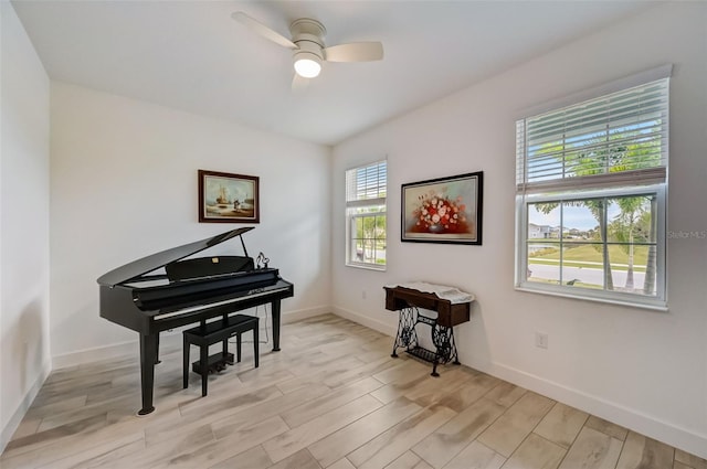 sitting room featuring light wood-style flooring, ceiling fan, and baseboards