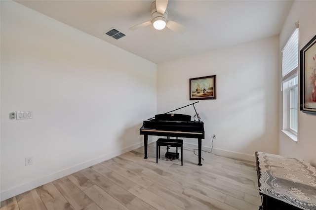 living area featuring a ceiling fan, baseboards, and light wood finished floors