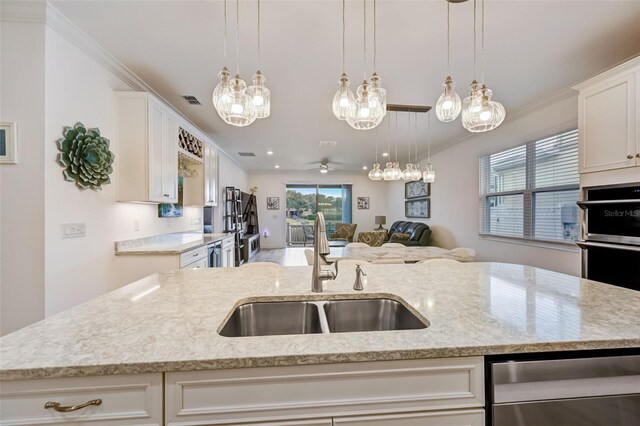 kitchen with a sink, open floor plan, stainless steel dishwasher, light stone countertops, and pendant lighting
