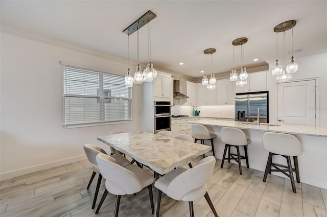 dining area featuring crown molding, light wood finished floors, baseboards, and recessed lighting