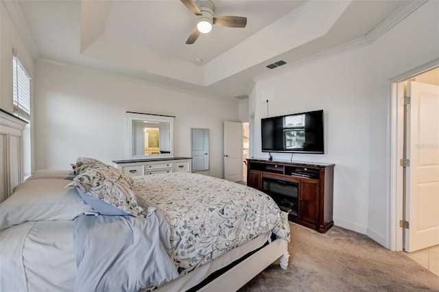 bedroom with light colored carpet, a tray ceiling, baseboards, crown molding, and ceiling fan