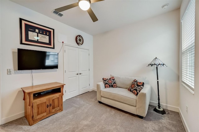 sitting room featuring ceiling fan, light colored carpet, healthy amount of natural light, and baseboards
