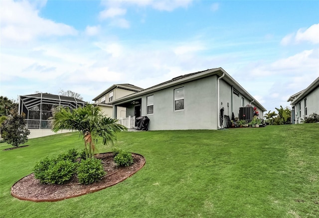 rear view of house featuring stucco siding and a yard