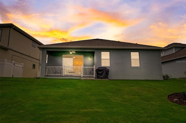 back of property at dusk featuring stucco siding and a ceiling fan