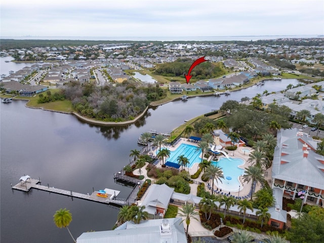 view of property location with a large body of water, a pool, and nearby suburban area
