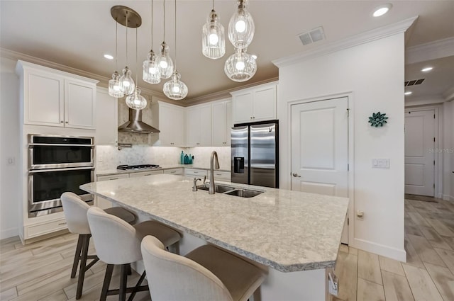 kitchen with appliances with stainless steel finishes, a sink, crown molding, backsplash, and wood tiled floors
