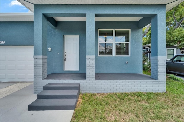 6097 Vermont Ave, New Port Richey, FL 34653 - property entrance with a porch, stucco siding, an attached garage, and brick siding