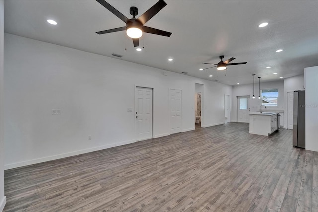 6097 Vermont Ave, New Port Richey, FL 34653 - unfurnished living room with ceiling fan, a sink, wood finished floors, recessed lighting, and baseboards
